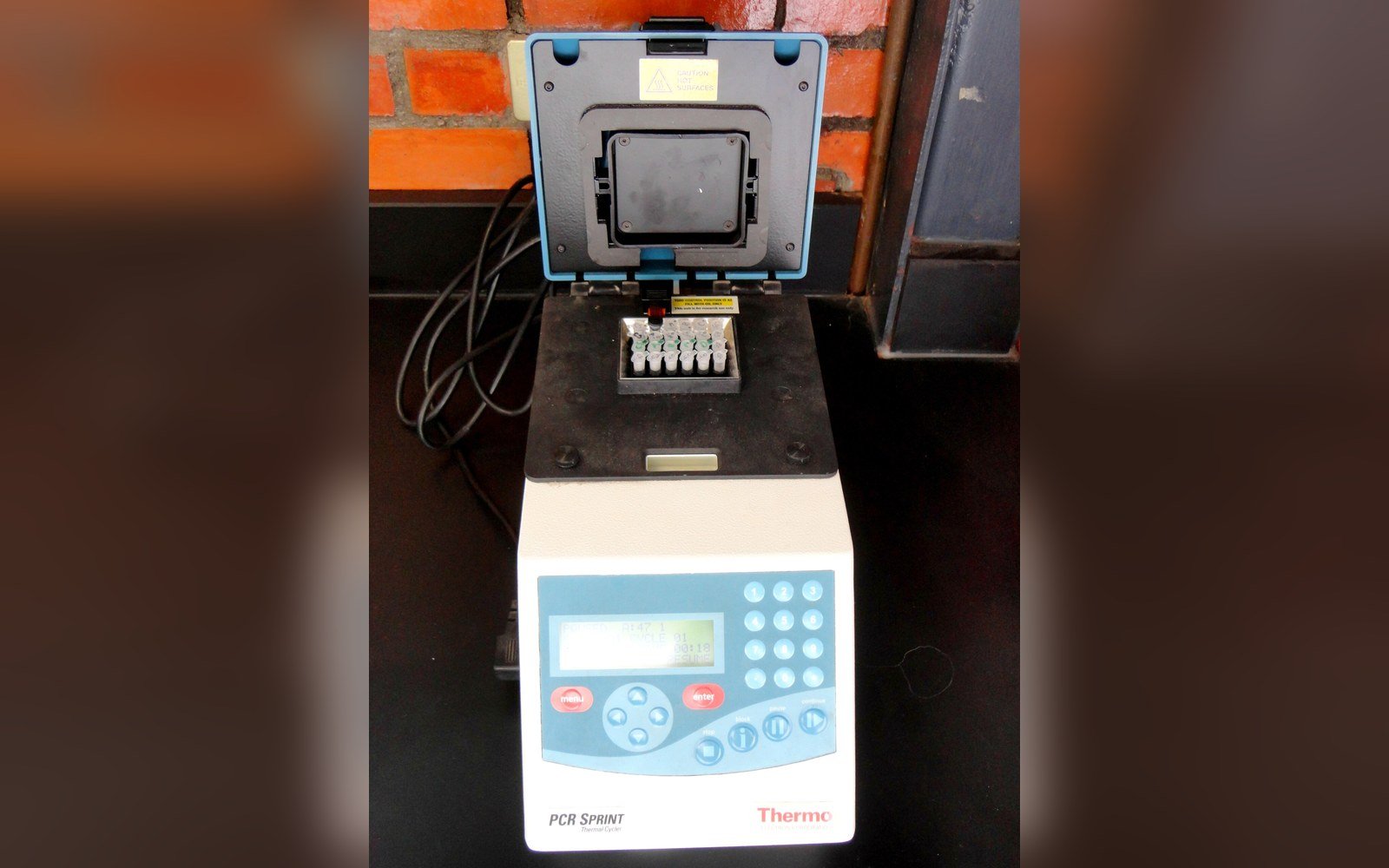 Open thermal cycler with sample tubes loaded, control panel reading Thermo PCR Sprint